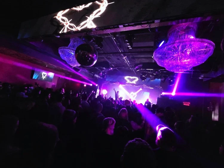 Concert crowd with purple laser lights and chandeliers
